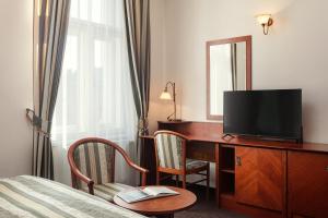 um quarto de hotel com uma secretária, uma televisão e uma cama em Amigo City Centre em Praga
