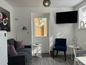 a living room with a couch and a tv on a wall at Hartshorne House in Telford