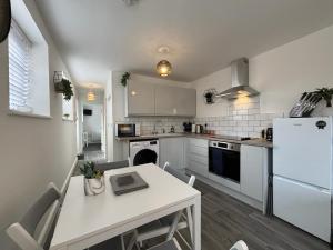 uma cozinha com uma mesa e um frigorífico branco em Hartshorne House em Telford