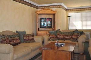 sala de estar con 2 sofás y TV en Travelers Inn Manteca, en Manteca