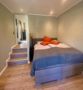 a bedroom with a bed with orange pillows and a staircase at Little Lopsi in Detmold