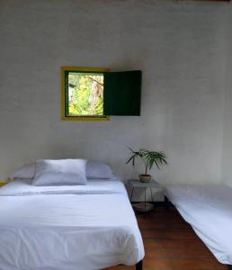 a bedroom with two white beds and a window at BOSQUE DE NIEBLA in Pijao
