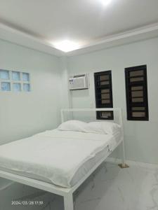 białe łóżko w białym pokoju z oknem w obiekcie MaNelly Guest House Hotel w mieście Donsol