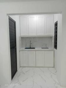 a kitchen with white cabinets and a sink at MaNelly Guest House Hotel in Donsol