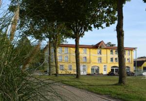 a yellow building with trees in front of it at Speicher-Appartement in Klein Upahl