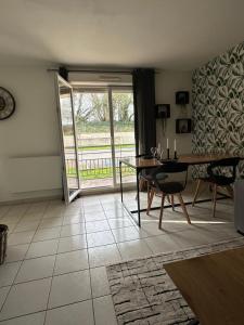 a living room with a table and a glass door at Appartement de Charles in Roye