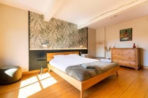 1 dormitorio con 1 cama y una pintura en la pared en Côté cour, côté source chambre d'hôtes en Chaudfontaine