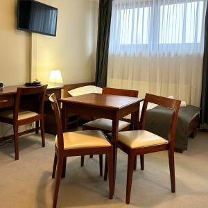 um quarto com uma mesa e cadeiras e uma cama em Hotel Vesta Centrum Konferencyjno Wypoczynkowe em Jelesnia