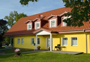 a yellow house with an orange roof at Seehaus-Studio in Klein Upahl