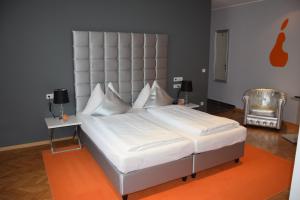 アムシュテッテンにあるStadthotel Gürtlerのベッドルームに大きな白いベッド(大型ヘッドボード付)が備わります。