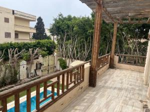 einen Balkon mit einem Holzgeländer und einem Pool in der Unterkunft El dakroury king mariout villa in Naj‘ al Aḩwāl