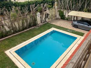 ein Pool in einem Garten mit einem Zaun in der Unterkunft El dakroury king mariout villa in Naj‘ al Aḩwāl