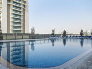 a large swimming pool with blue chairs and a building at Frank Porter - Elite Sports Residence in Dubai