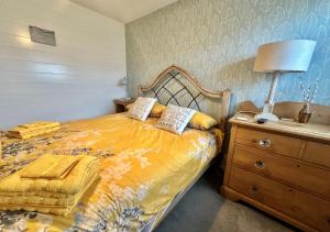 a bedroom with a bed with a lamp and a dresser at Gilfach Ceidio in Morfa Nefyn