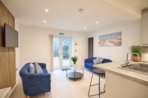 a kitchen and living room with blue chairs and a counter at Modern 5 Bedroom Fully upgraded with Free Parking in Earlham