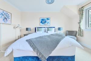um quarto com uma cama branca e um cobertor azul em Kinkell House B&B em Cononbridge