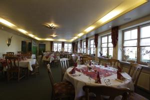 a dining room with tables and chairs and windows at Haus Waldesruh in Hollnich