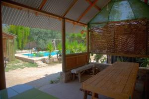 een paviljoen met een houten tafel, een bank en een zwembad bij Alme cabañas Olmué in Granizo