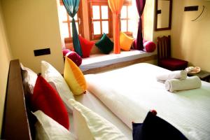 two beds in a room with colorful pillows at hotel paru palace jaisalmer in Jaisalmer