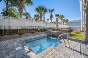 a swimming pool in a yard with a fence and palm trees at North Myrtle Beach Home - Walk to the Ocean! in Myrtle Beach