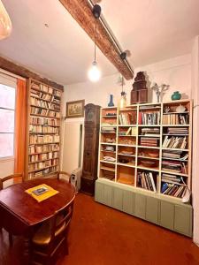 a room with a table and a book shelf with books at Abbaye - Appartement spacieux au coeur du Vieux-Nice in Nice