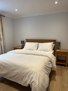 1 dormitorio con 1 cama grande con sábanas y almohadas blancas en The Hannexe en Wadebridge