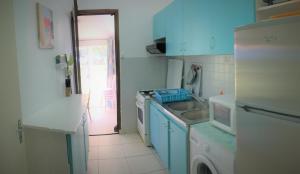 uma cozinha com armários azuis e uma máquina de lavar e lavatório em Honey & Sweet Dream - lagon de l'Ermitage avec piscine em Saint-Paul