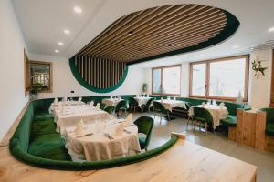 a restaurant with white tables and green chairs at Olimpionico Hotel in Castello di Fiemme