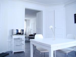 un soggiorno bianco con tavolo e sedie bianchi di Bel Appartement Coeur de Ville a Troyes
