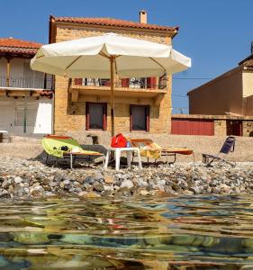 una mesa y sillas bajo una sombrilla junto al agua en Waveside Sanctuary - Luxurious Seastone Villa, en Avía
