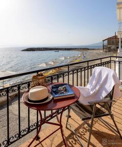una mesa con un sombrero sentado en una silla junto a la playa en Waveside Sanctuary - Luxurious Seastone Villa, en Avía
