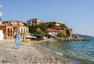 una playa con sombrillas, edificios y agua en Waveside Sanctuary - Luxurious Seastone Villa, en Avía