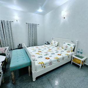 una camera con un letto bianco e una panca blu di Tringrahi Vraj Mahal a Vrindāvan