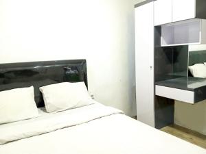 1 dormitorio con cama blanca y cabecero negro en Saijaan Yogyakarta Mitra RedDoorz, en Kejayan