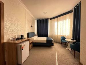 a hotel room with a bed and a table and chairs at Aurora Hotel in Tashkent