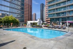 a large swimming pool in a city with tall buildings at Blueground DTLA pool courtyard near dining LAX-1202 in Los Angeles