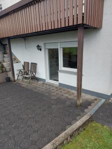 a patio with two chairs next to a house at Widmann‘s Ferienquartier in Wiehl