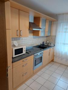 a kitchen with wooden cabinets and a microwave and a sink at Widmann‘s Ferienquartier in Wiehl