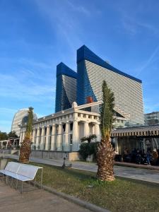 un bâtiment avec deux palmiers devant lui dans l'établissement Elite Class Sea View Aparthotel In Orbi City Batumi, à Batoumi