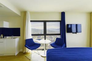 バトゥミにあるElite Class Sea View Aparthotel In Orbi City Batumiのベッド1台、椅子2脚、窓が備わる客室です。