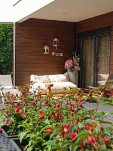 een patio met een bank en een bos met rode bloemen bij Norte de Santillana in Santillana del Mar