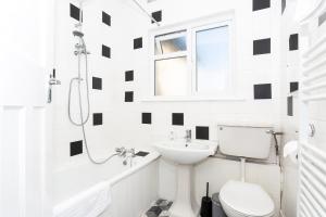 a white bathroom with black and white tiles at Large 4 Bed in Southend, near shops/cafés/beach! in Southend-on-Sea