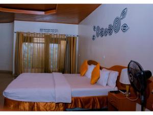 una camera da letto con un letto con lenzuola bianche e cuscini arancioni di Igitego Hotel Remera a Kigali