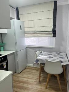 a small kitchen with a table and a refrigerator at Квартира in Sätbaev
