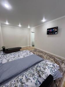 ein Schlafzimmer mit einem Bett und einem TV an der Wand in der Unterkunft Квартира in Sätbaev