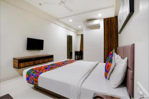 um quarto com uma cama e uma televisão na parede em FabHotel La Victoria em Surate