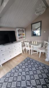 a living room with a tv and a white dresser at No. 4 Sunny Lodge By The Sea in Aberystwyth