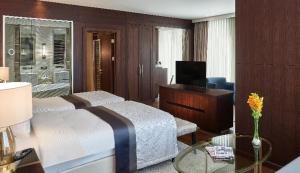 een slaapkamer met een bed, een bureau en een televisie bij Elite World Grand Istanbul Basın Ekspres in Istanbul