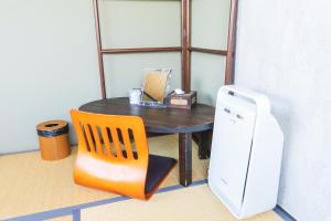 uma mesa com uma cadeira e uma mesa com um frigorífico em Bigtree Guesthouse em Izumi-Sano