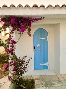 eine blaue Tür auf einem Gebäude mit rosa Blumen in der Unterkunft LASSION GOLDEN BAY Sea view in Sitia